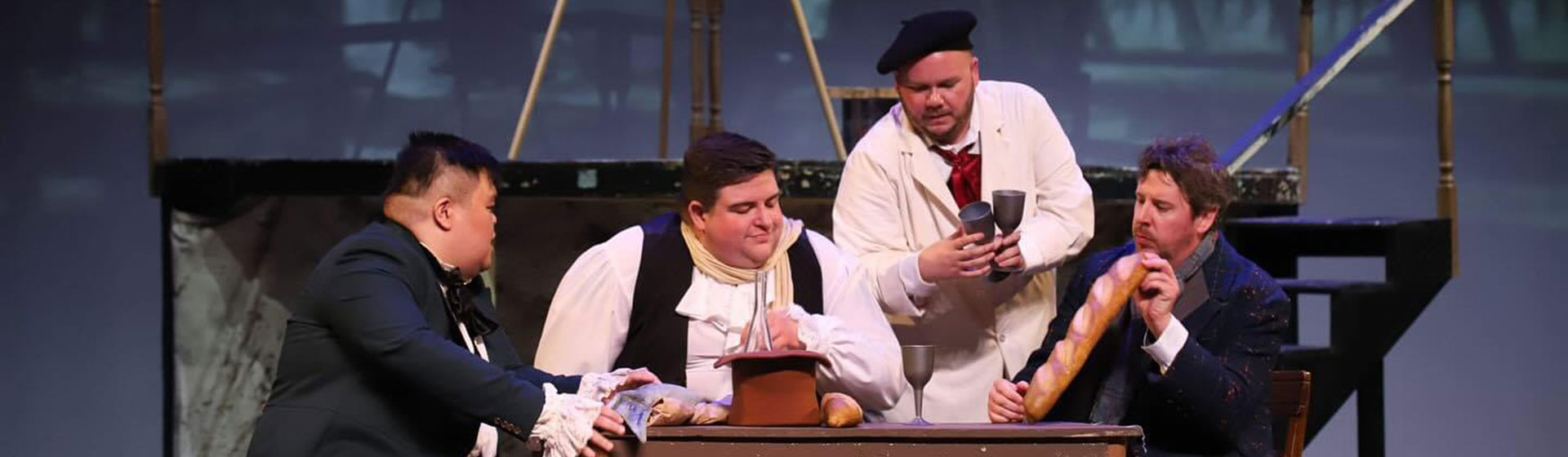 Photo of an opera with four men at a table